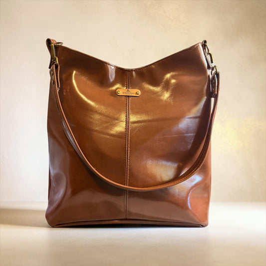 NspiVibe cognac brown hobo handbag with a polished finish, slouchy silhouette, and gold-tone hardware details.