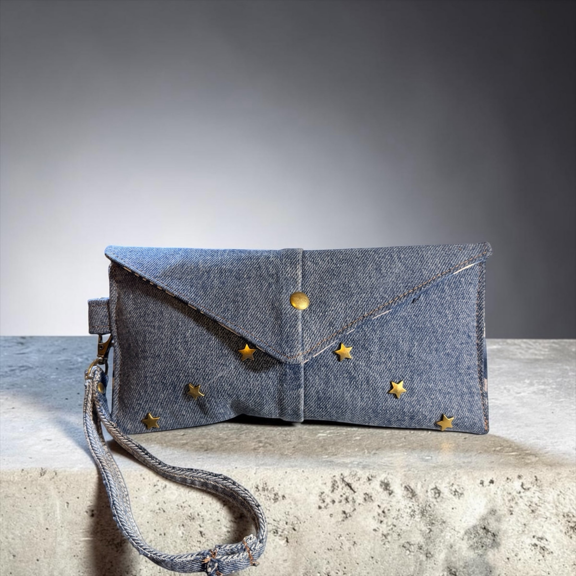 NspiVibe blue denim envelope wristlet clutch featuring gold-tone star studs and a secure snap-button closure.